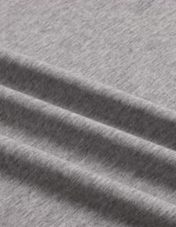 A close-up of a grey premium cotton T-shirt fabric, featuring a soft, textured finish and gentle folds.