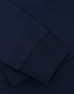 A navy blue long sleeve tee shirt featuring close-up details of the fabric and cuffs, with a logo present.