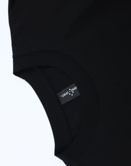 A black unisex heavy cotton oversized tee featuring a tag with branding on the inner neckline.