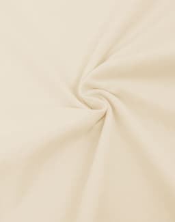 A close-up of light beige fabric, showcasing a smooth, oversized cotton texture with a flowing twist.