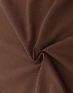 A close-up of brown fabric displaying a smooth, soft texture with a swirling pattern. There is a branding logo visible.