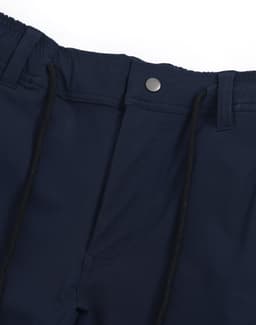 A pair of navy blue water repellent flexi work pants featuring a button and drawstring waist. The garment has a logo.
