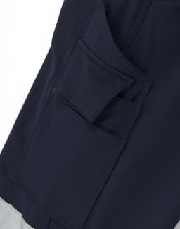 A close-up of navy blue work pants featuring multiple utility pockets and a branding logo.