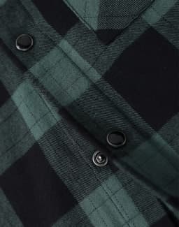 A close-up of a black and green flannel plaid shirt featuring button details. The shirt has a classic check pattern.