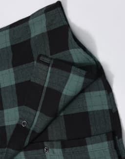 A unisex flannel plaid shirt featuring green and black check patterns, with button-up details and a logo.