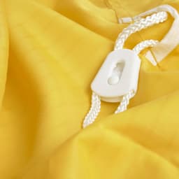 A yellow laundry bag made of 100% polyester, featuring a white drawstring closure and a plastic toggle.