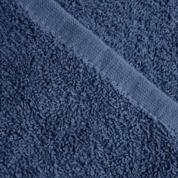 A navy blue face washer with a textured surface and a smooth edge, featuring a logo or branding.