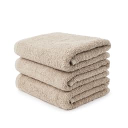A stack of three large hand towels in a light beige colour, featuring a soft, plush texture.