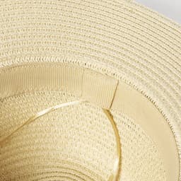 A close-up of a beige brim hat, featuring a textured woven design and a smooth inner band.