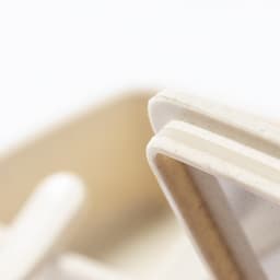 A light-coloured lunch box with a minimalist design, featuring a smooth surface and a visible inner compartment.