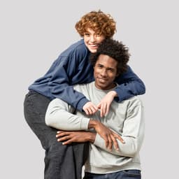 A grey hoodie worn by a man and a navy hoodie worn by a woman, both smiling and posing together.