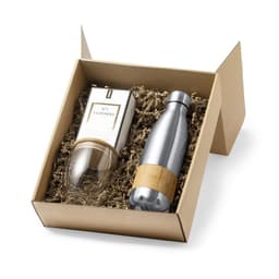 A gift set featuring a silver drink bottle and a clear glass, presented in a beige box with crinkle paper.