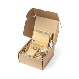 A gift set in a cardboard box, featuring a wireless charger, USB drive, wooden keyring, and cables, with straw filling.