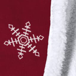 A red blanket with a white snowflake design and a fluffy white lining. It features branding.
