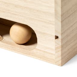 A wooden box with a small circular wooden ball partially visible through a hole. The box has a natural finish.