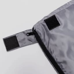 A grey bag with a zippered closure and Velcro fasteners, featuring a smooth, shiny fabric. It has a branding logo.
