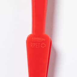 A red handheld fan made from recycled materials, featuring a branding logo on the handle.