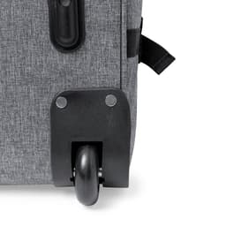 A wheeled bag in a grey fabric, featuring a black wheel and metal fasteners for stability.