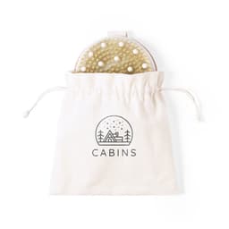 A hairbrush with a round head is partially visible inside a cream drawstring bag featuring a logo.