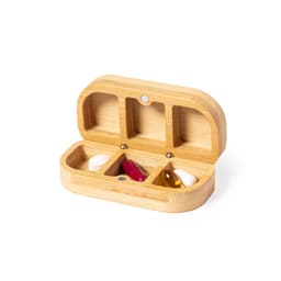 A bamboo pill organiser with three compartments, containing various tablets and capsules in red, white, and yellow.