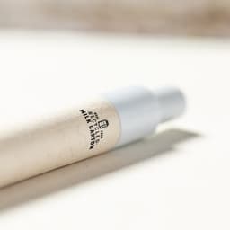 A pen with a recycled milk carton body and a silver tip, featuring a logo on the side.