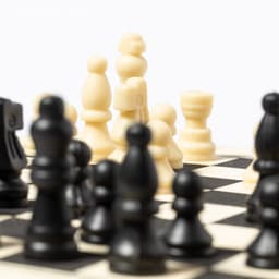 A chessboard featuring black and cream pieces in strategic positions, highlighting the game's competitive nature.