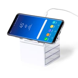 A wireless charger in white with a smartphone resting on top, connected by a cable.