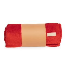 A rolled red blanket featuring a tan band around it. The blanket has a soft, plush texture and includes a logo.