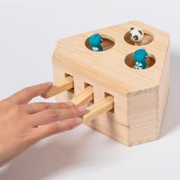 A wooden game with three coloured figures and four holes, featuring a hand interacting with the game.