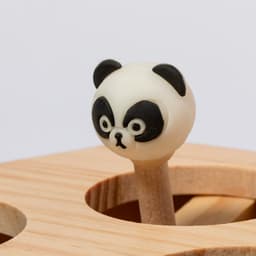 A wooden game piece featuring a panda head with black and white detailing atop a light wooden stick.