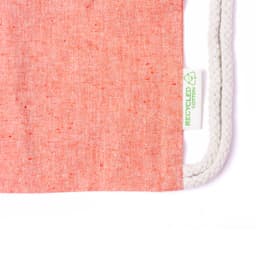 A drawstring bag in a soft coral hue, featuring natural rope straps and a tag indicating recycled cotton material.