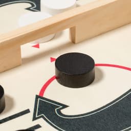A black game piece rests on a board featuring red and white arrows and a wooden barrier. The board has a fun design.