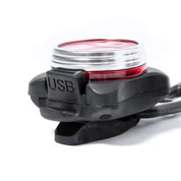 A bike light with a black body and red lens, featuring a USB port for charging.