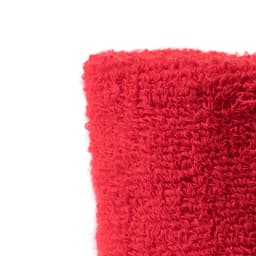 A close-up of a red, textured fabric, likely a wristband, showing its fuzzy, soft surface.