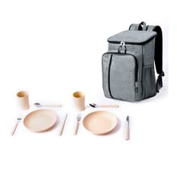 A grey cooler backpack stands beside a set of camping dishes, including plates, cups, forks, knives, and spoons.