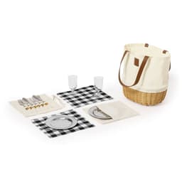 A cream picnic basket with a brown strap, containing black and white checkered placemats, plates, cutlery, and glasses.