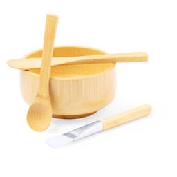 A bamboo bowl with two utensils, including a spoon and a flat applicator, all in natural wood tones.