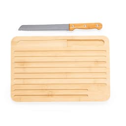A bamboo chopping board with grooves and a serrated knife positioned on top.