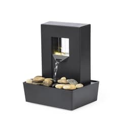 A black indoor water fountain with a square design, featuring flowing water and a bed of smooth pebbles.