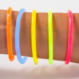 A set of five glowing bracelets in orange, blue, yellow, neon green, and pink worn on a wrist.