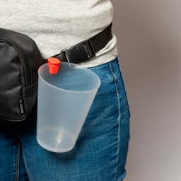 A plastic cup with a red lid, attached to a belt, alongside a black pouch on denim shorts.