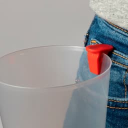 A transparent plastic cup with a red handle, partially inserted into the pocket of denim jeans.