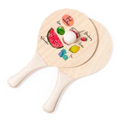 Two wooden beach rackets featuring colourful fruit illustrations, including a watermelon, lemon, and strawberries, with a white ball.