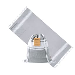 A grey drawstring bag made of fabric, accompanied by a matching grey beach towel, featuring a branding label.