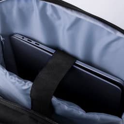 A black backpack with a light blue interior, featuring a pocket holding a tablet. The bag has a logo.