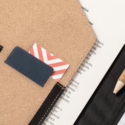 A tan folder featuring a card slot with two cards, alongside a pencil and a sheet of paper.