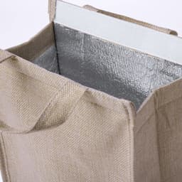 A cooler bag in a natural beige colour with a silver insulated interior and sturdy handles. It features a logo.