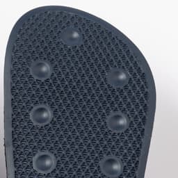 A close-up of a black thong's sole, featuring textured patterns and small grip dots for traction.