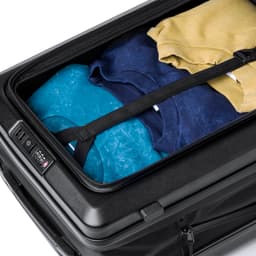 A wheeled bag in black, filled with folded shirts in blue, navy, and yellow, secured with straps.
