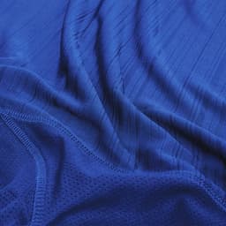 A blue T-shirt with a textured fabric, featuring a subtle pattern and a logo. The material appears lightweight and smooth.